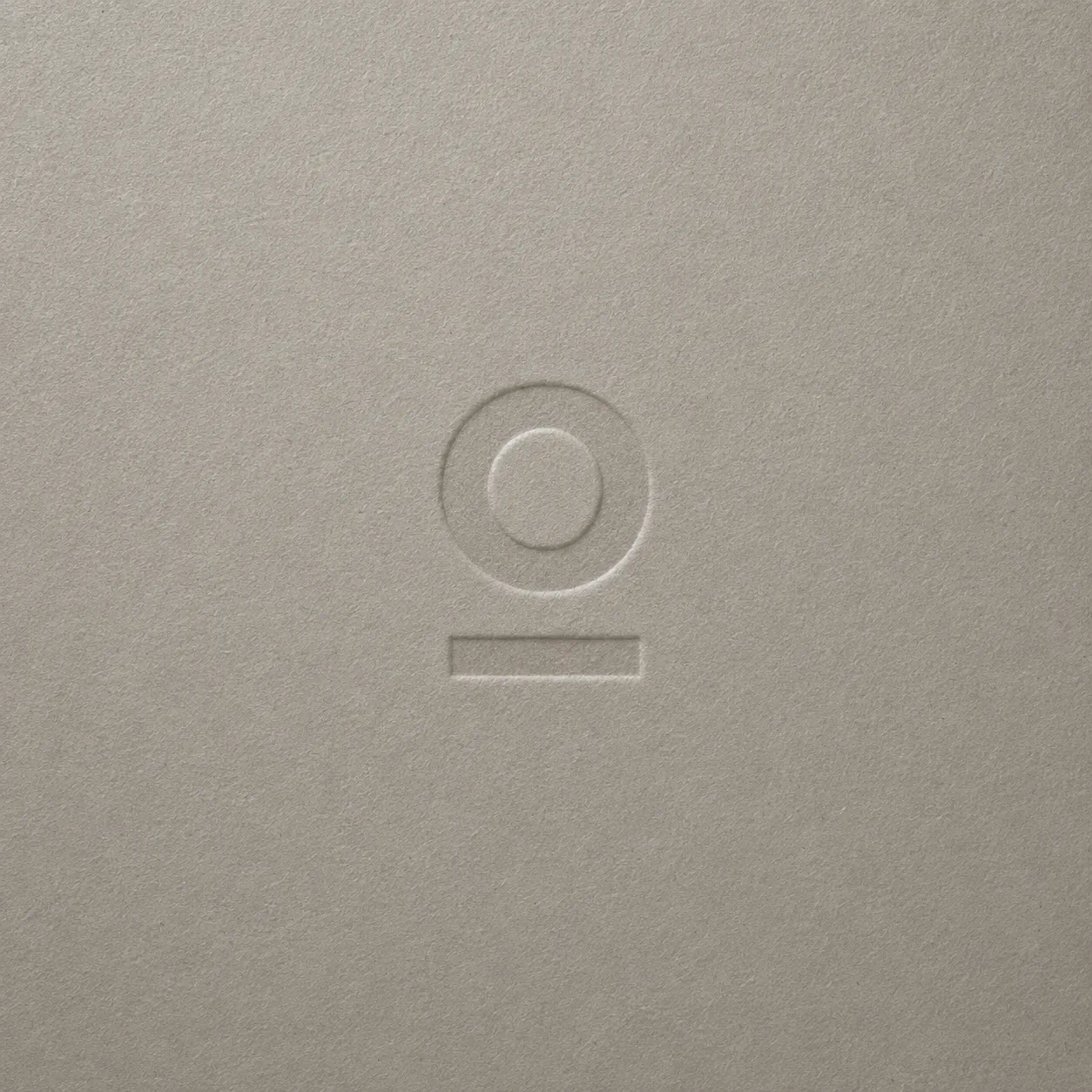 Embossed identity mark for a men's coaching program on a textured taupe surface