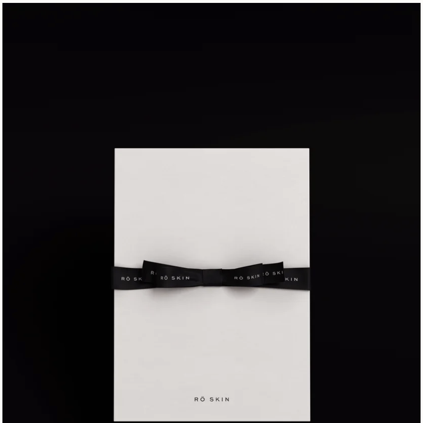 RŌ SKIN skincare packaging with a black ribbon on a dark background